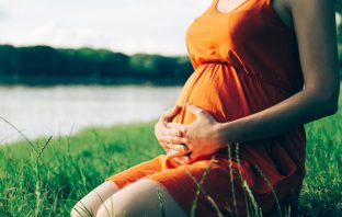 Pregnant woman, holding in hands bouquet of daisy. Image credit: Thinkstock