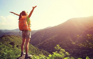 Woman opening her arms up in happiness on top of a mountain. Image credit: Thinkstock