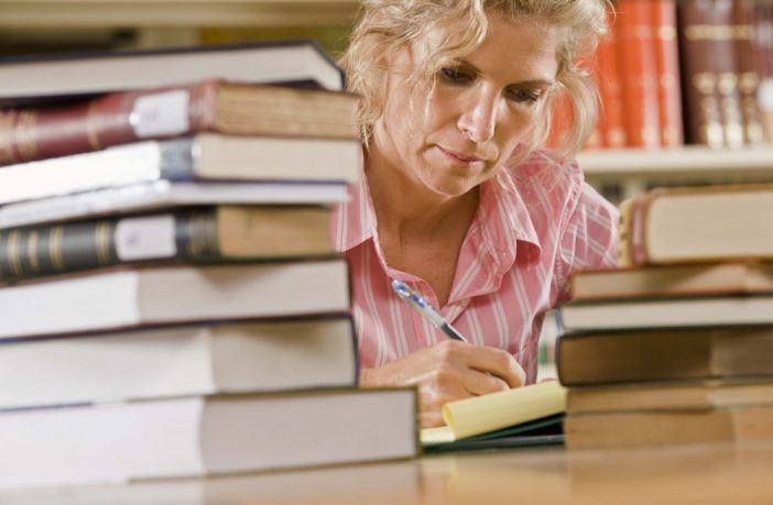 Mature female student with books in library