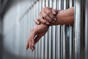 Photo of hands through prison bars