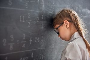 Girl holding head against a school blackboard