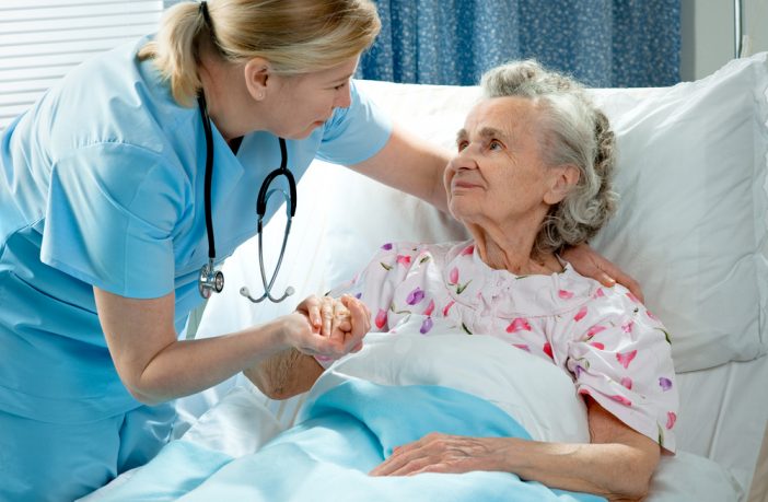 Photo of nurse caring for elderly lady in hospital bed