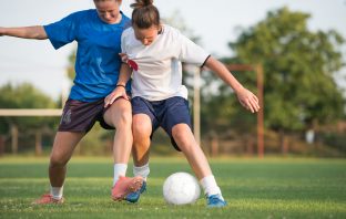 Two women tackling for a football