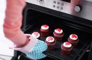 Woman taking cupcakes out of oven