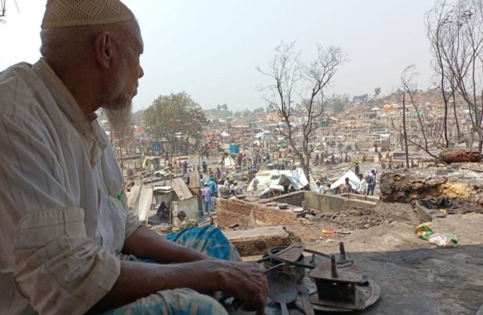 An elderly Rohingya Refugee man looks out upon the devastation caused by the fires that burned down the homes of thousands in April 2021 Photo by Mohamned Zobair