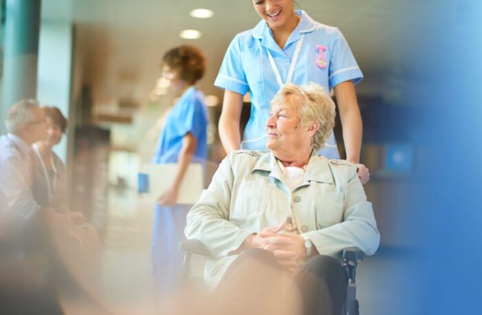 Female nurse pushing a patient in a wheelchair