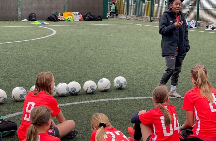 Young women speaking to children about football