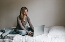 Student sitting on a bed with a laptop