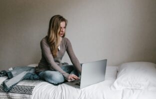 Student sitting on a bed with a laptop