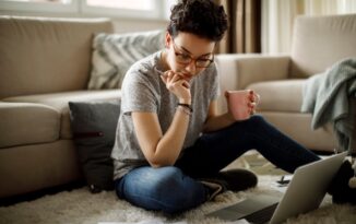 Image of a student with laptop and papers on the floor around them