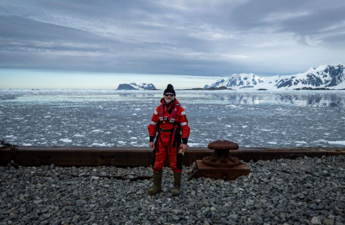 Andy dressed in warm clothing with a backdrop of Antarctica