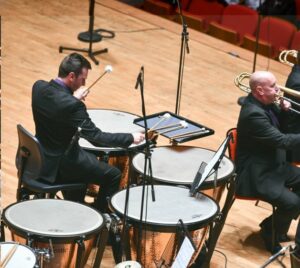 Man in a black suit playing the drums