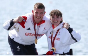 Gregg and rowing partner Lauren wearing Team GB kit, smiling at the camera with Paralympic Gold medals around their necks.