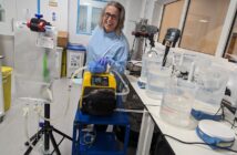 Emilie wearing a blue lab coat surrounded by scientific equipment,