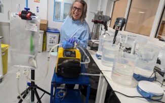 Emilie wearing a blue lab coat surrounded by scientific equipment,