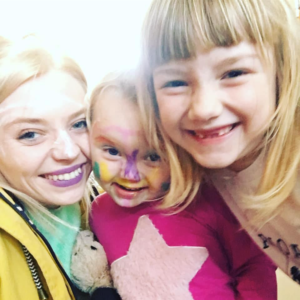 A young blonde haired woman with her two young children.