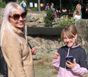 A young blonde-haired woman with her child at a wildlife park.